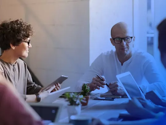 ludzie siedzący przy biurku trzymający tablety w rękach