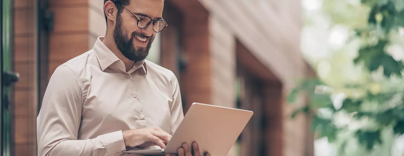 Na zdjęciu widać mężczyznę korzystającego z laptopa.