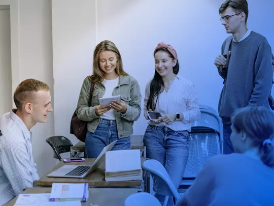 grupa zadowolonych studentów patrząca na mobilne urządzenia