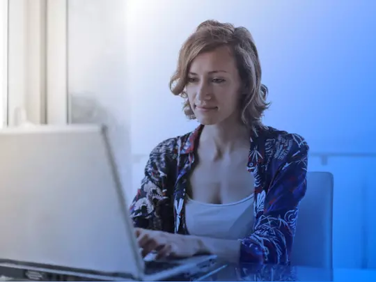 Uśmiechnięta kobieta spoglądająca na laptop