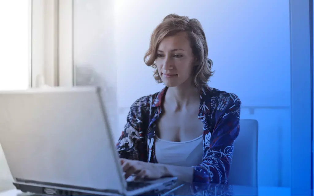 Uśmiechnięta kobieta spoglądająca na laptop